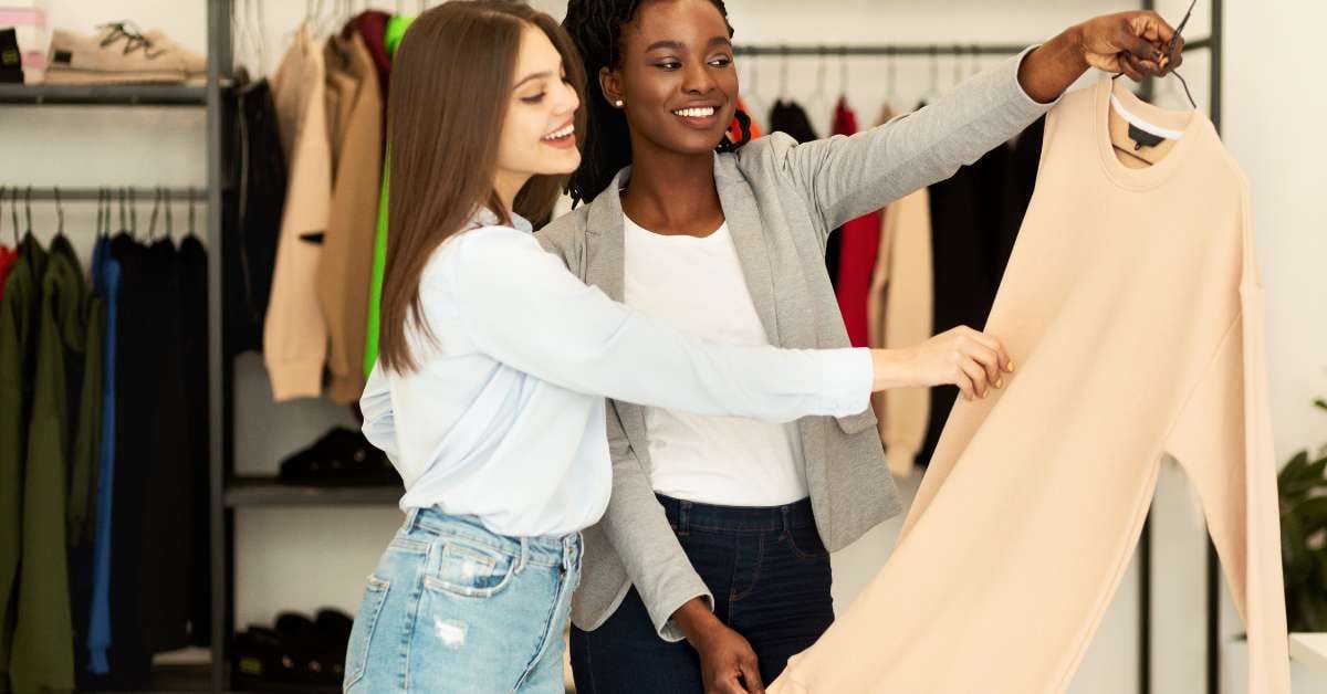 Two women stand in a retail store looking at a shirt that was recommended to them from personalization technology.