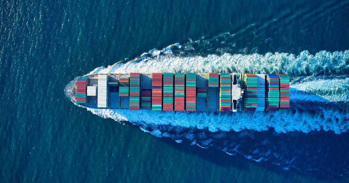 Image of cargo ship full of supply chain cargo sailing across the ocean. 