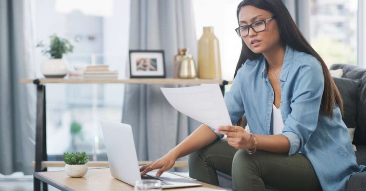 Woman reviews regulatory compliance paperwork for her company while sitting on a chair.