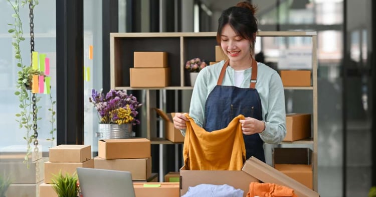 Woman opens a delivery box filled with clothing items she purchased online.