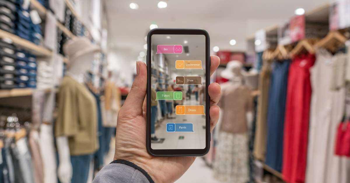 Hand holding smart phone use AI-powered AR application to check information in a large clothing shop.