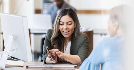 Woman shows teller her banking account information on the newly developed app. 