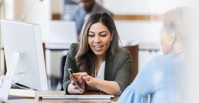 Woman shows teller her banking account information on the newly developed app. 