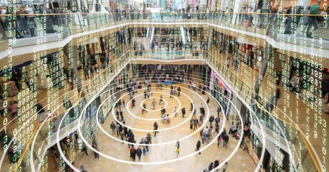 Image of a crowded mall with transparent digital cloud coding represimg cloud migration hovering above everyone.