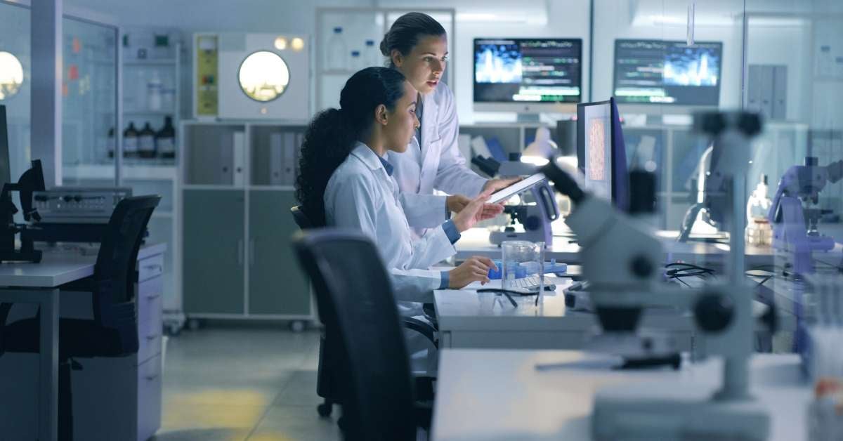 Two healthcare professionals look at clinical trials information inside of a laboratory setting.