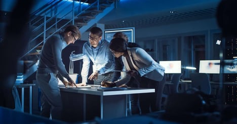 Image of a MLOPS team looking over documents on a table.