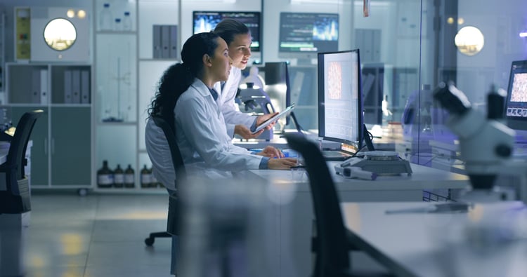 2 research clinicians look at a computer monitor to review data on their system's application.