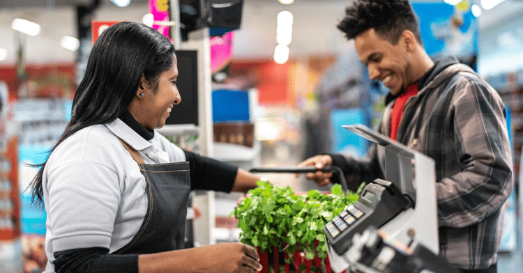 Man and woman stand at a grocery checkout ringing up items.